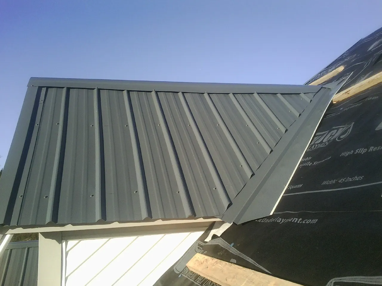 Gray metal roof panels going on over a garage gable in Delmar